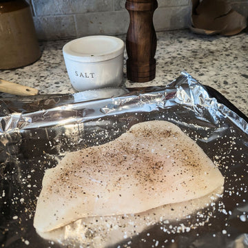 Halibut filet being seasoned on counter