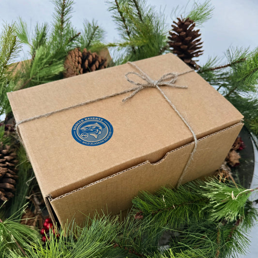 Brown paper-wrapped box with a twine bow and Kodiak Reserve logo on a bed of pine greenery