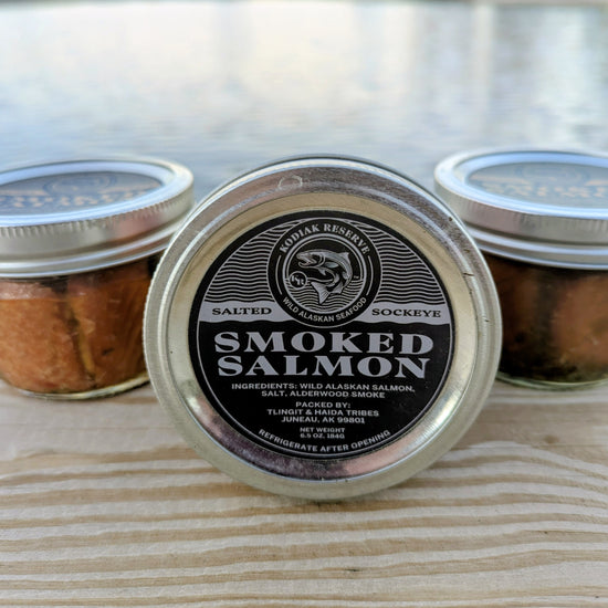 3 jars of salmon on a dock in front of water